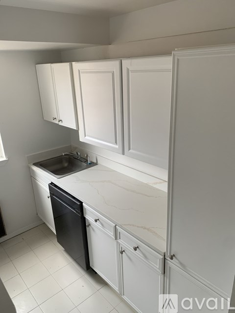A kitchen with white cabinets and a black dishwasher.