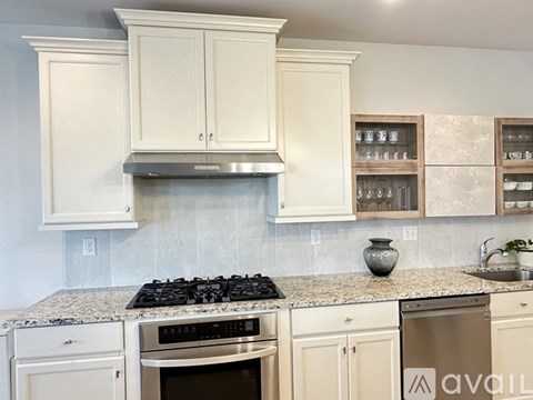 A kitchen with white cabinets and a granite countertop.