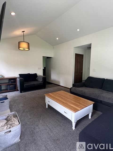 A living room with a black couch and a wooden coffee table.