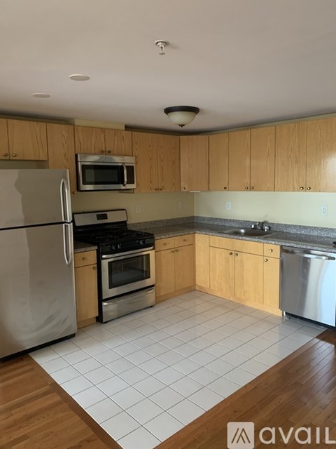 A kitchen with wooden cabinets and a white tile floor.