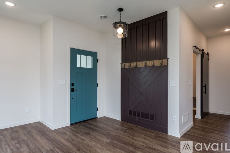 A room with a teal door and a wooden floor.