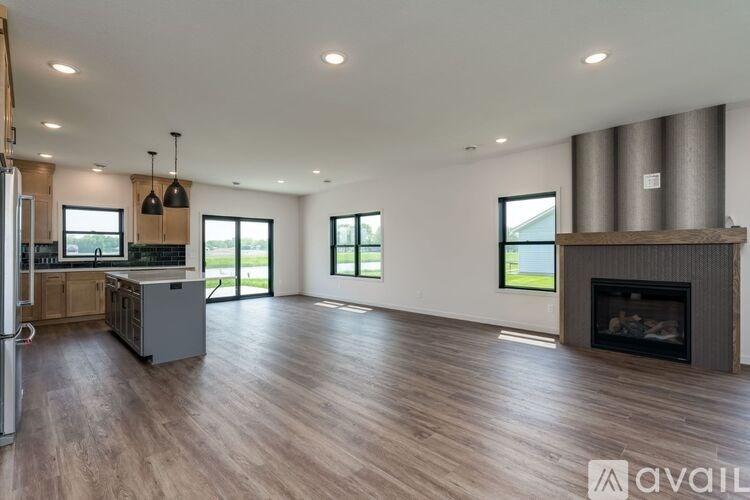A spacious living room with a fireplace and a kitchen area in the background.