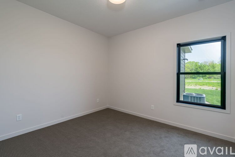 A room with a window showing a view of a green area outside.