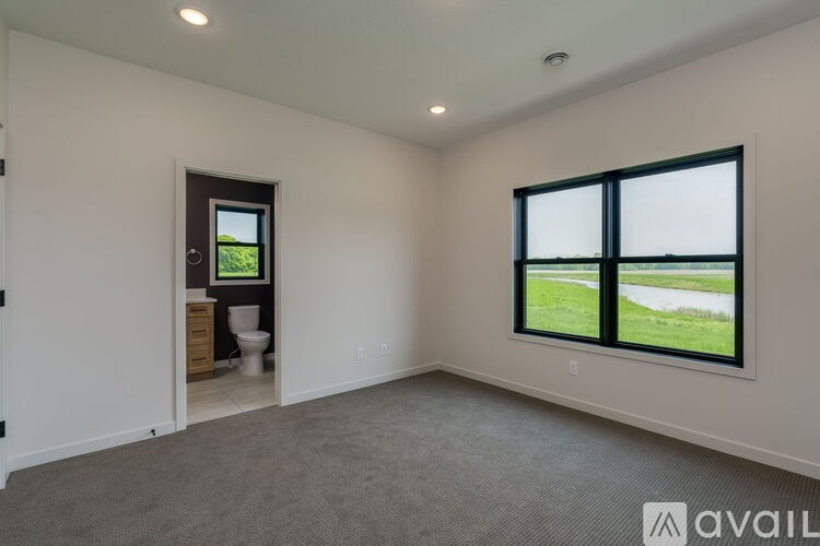 A room with a large window overlooking a green field.