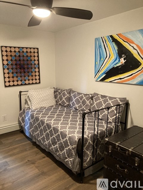 A bedroom with a bed, a ceiling fan, and two pieces of artwork on the wall.