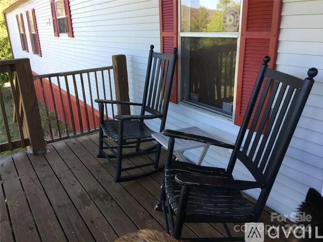Two black rocking chairs on a wooden deck.