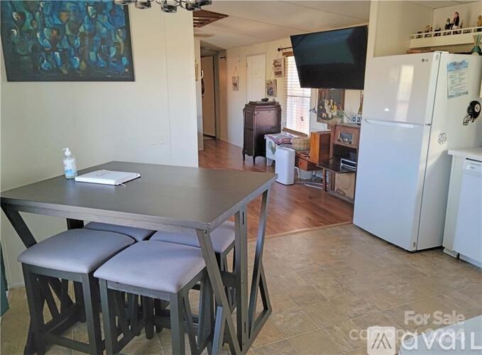 A kitchen with a table and chairs in the foreground and a refrigerator in the background.