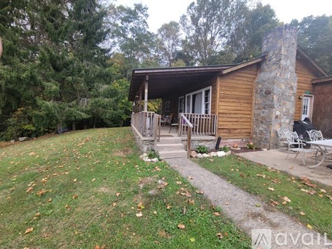 A wooden cabin with a stone chimney and a patio area.