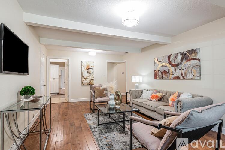 A living room with a glass table and a grey couch.