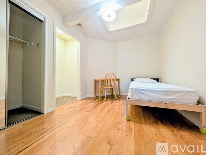 A bedroom with a bed, chair, and a glass door.