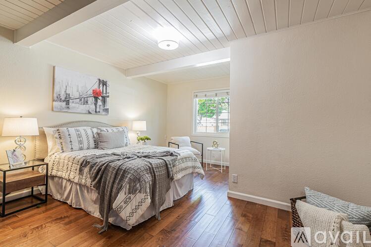A bedroom with a large bed and a painting on the wall.