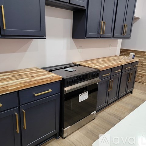 A kitchen with dark blue cabinets and a wooden countertop.