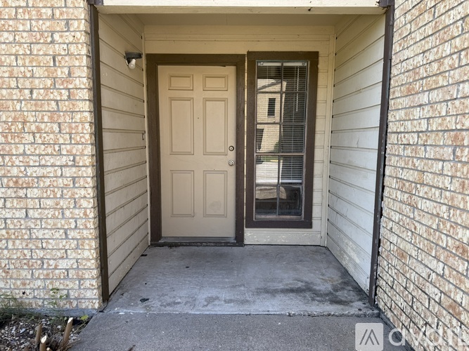 A white door is on the left side of a brick wall.