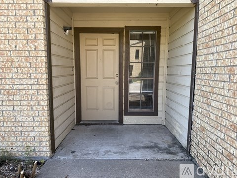 A white door is on the left side of a brick wall.