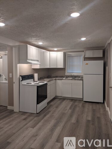 A kitchen with white cabinets and a wooden floor.