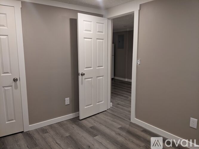 A room with a white door and a wooden floor.