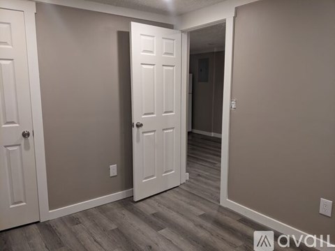 A room with a white door and a wooden floor.