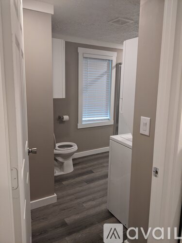 A bathroom with a toilet, sink, and window.