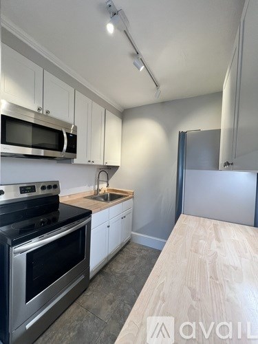 A kitchen with white cabinets and a wooden countertop.