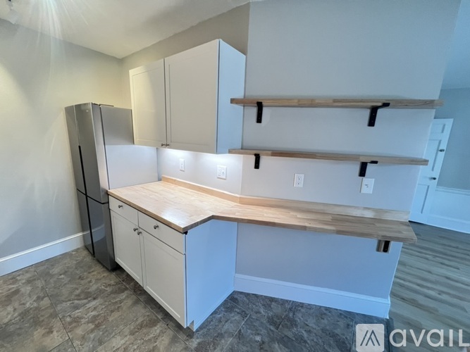 A kitchen with a refrigerator, cabinets, and a countertop.