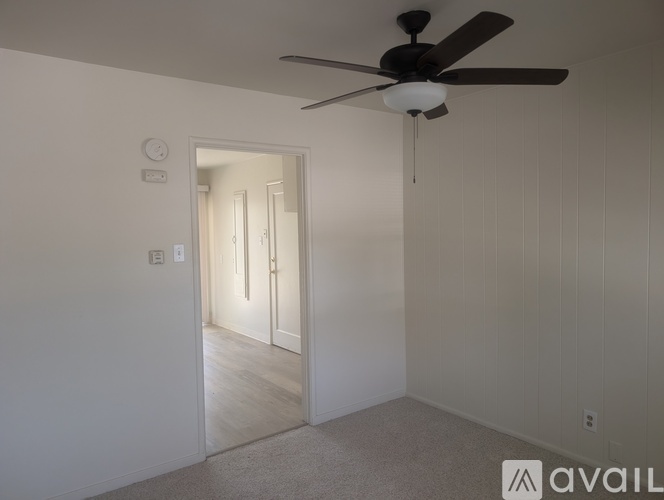 A room with a ceiling fan and a door leading to another room.