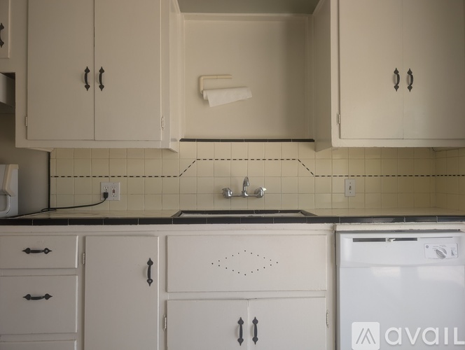A kitchen with white cabinets and a black countertop.