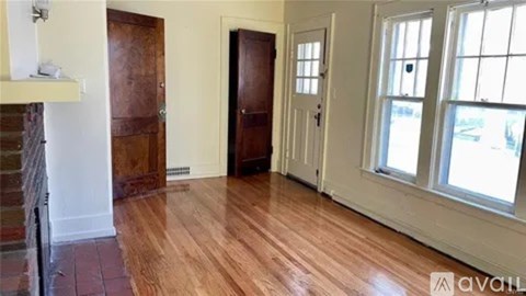 A room with wooden floors and a window showing a view of other buildings.