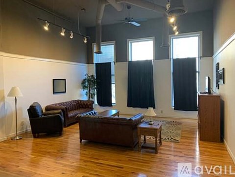 A living room with a brown leather couch and a wooden floor.