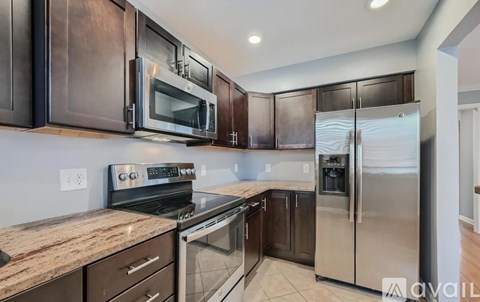 A kitchen with dark brown cabinets and stainless steel appliances.
