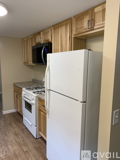 A kitchen with a white refrigerator, a stove, and wooden cabinets.
