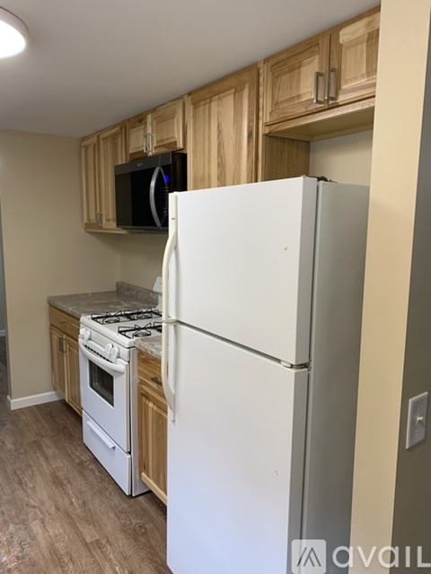 A kitchen with a white refrigerator, a stove, and wooden cabinets.