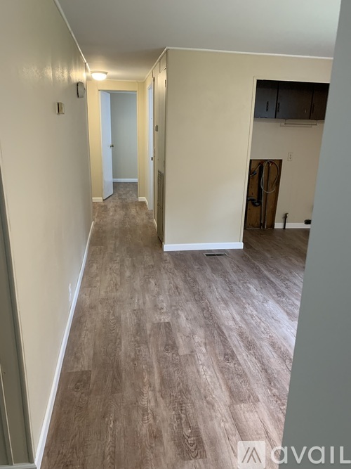 A long hallway with wood flooring and white walls.