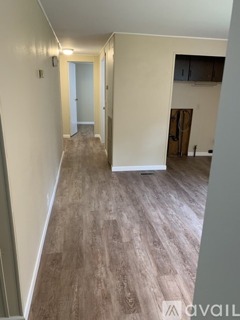 A long hallway with wood flooring and white walls.