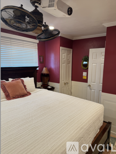 A bedroom with a bed, a fan, and a window with blinds.