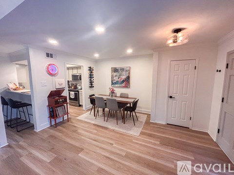 A dining room with a table set for four and a kitchen area in the background.