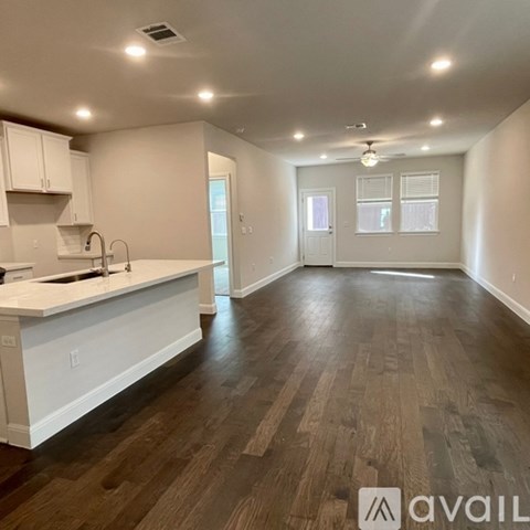 A spacious kitchen with white cabinets and a wooden floor.