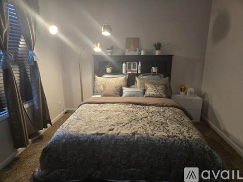 A bedroom with a large bed and a nightstand with a lamp.