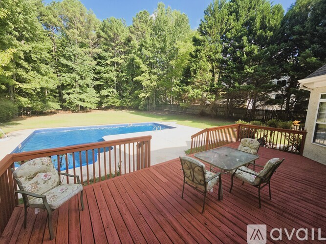 A wooden deck with a table and chairs overlooking a pool.
