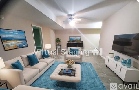 A living room with a white couch, a coffee table, and a painting on the wall.
