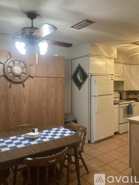 A kitchen with a table and chairs and a ceiling fan.