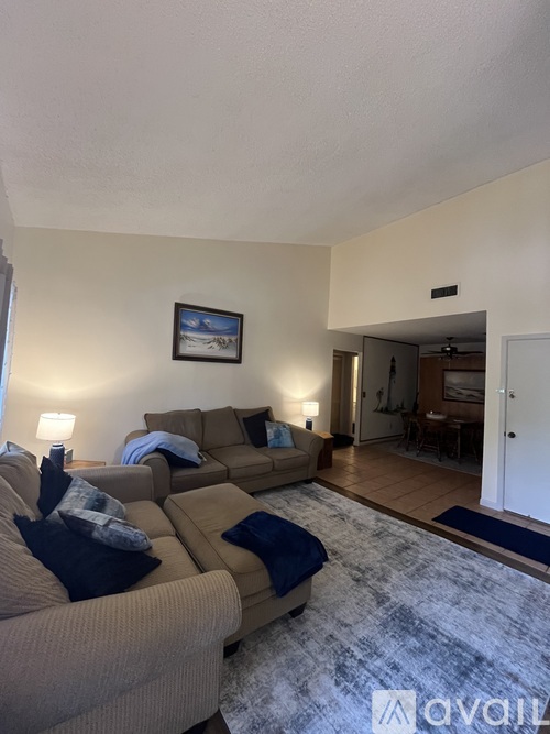 A living room with a tan couch and a blue rug.