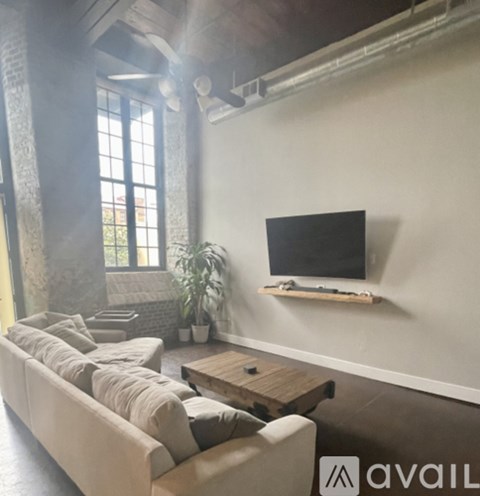 A living room with a couch, a coffee table, and a television on a shelf.