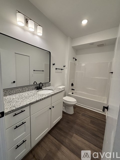A white toilet sits in a bathroom next to a white sink and a white rug.
