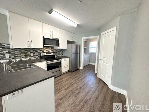 A kitchen with white cabinets and a black countertop.