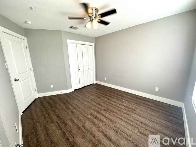 A room with a ceiling fan and wood flooring.