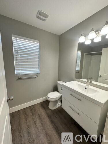 A bathroom with a toilet, sink, and mirror.