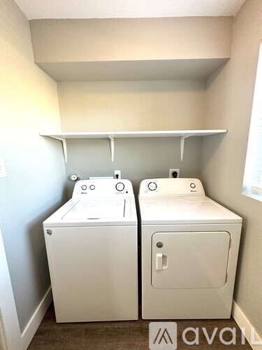 Two white washing machines in a small laundry room.