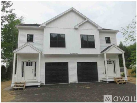 A two-story white house with a black garage door.