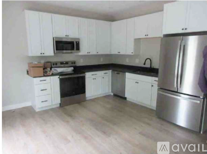A kitchen with white cabinets and a stainless steel refrigerator.