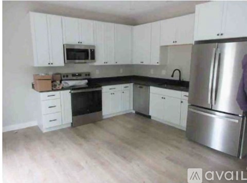 A kitchen with white cabinets and a stainless steel refrigerator.